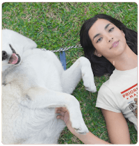 a woman laying on the grass with a dog